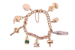 A charm bracelet featuring nine charms including examples of an Egyptian mummy charm, a 9ct gold