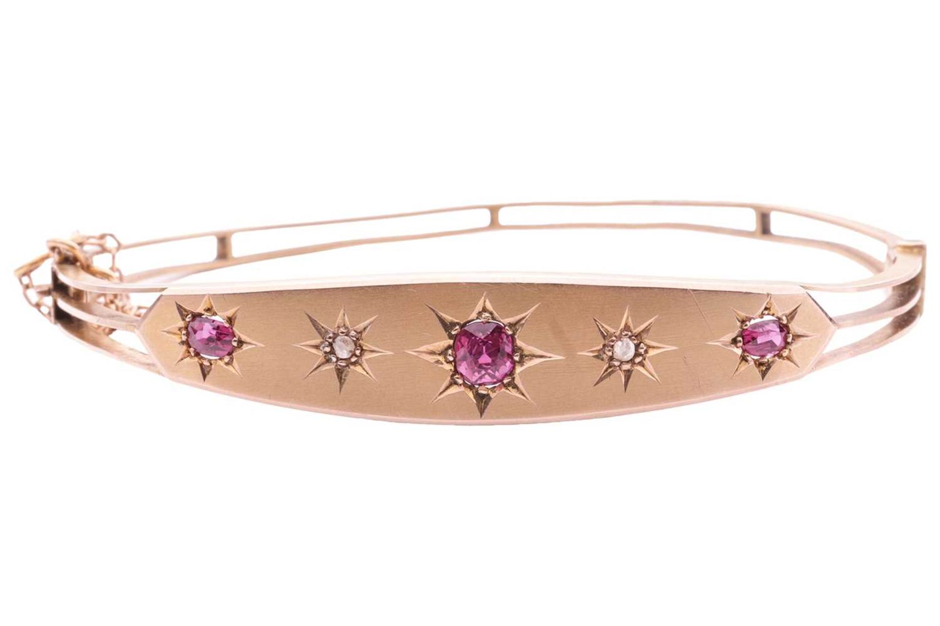 A late Victorian pink sapphire and diamond hinged bangle, front panel star-set with three graduated 