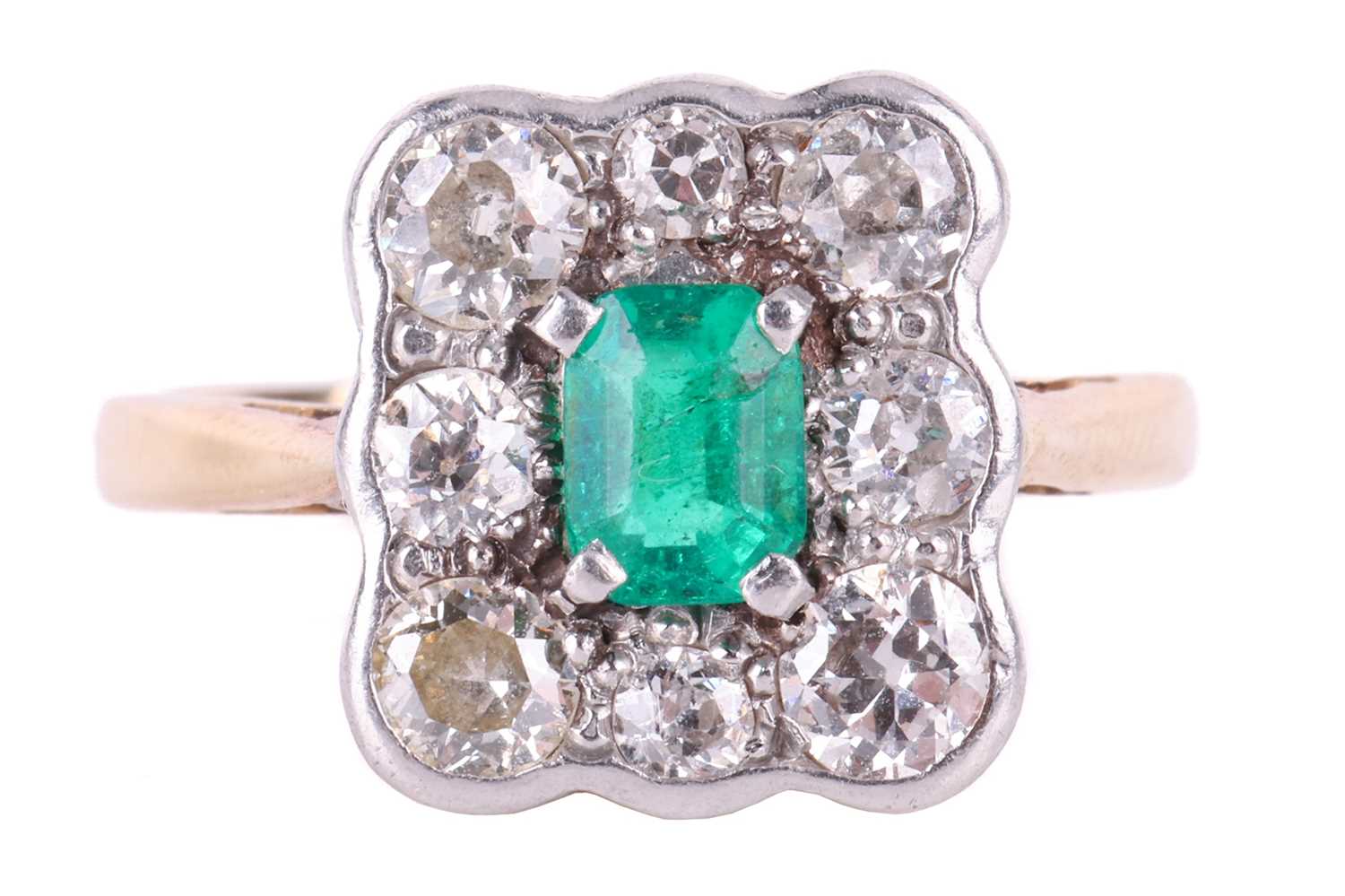 An emerald and diamond cluster ring, centred with an emerald-cut emerald of bright green colour, app