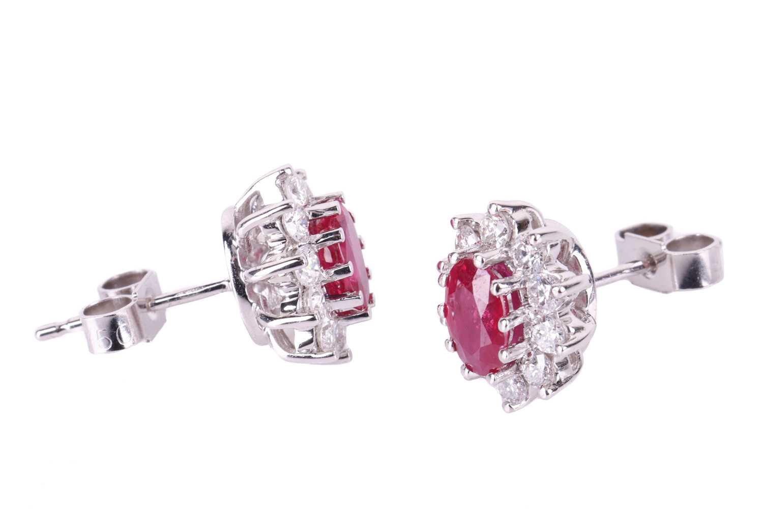 A pair of ruby and diamond cluster earrings, the central oval-cut rubies measuring approximately 6mm - Image 2 of 3