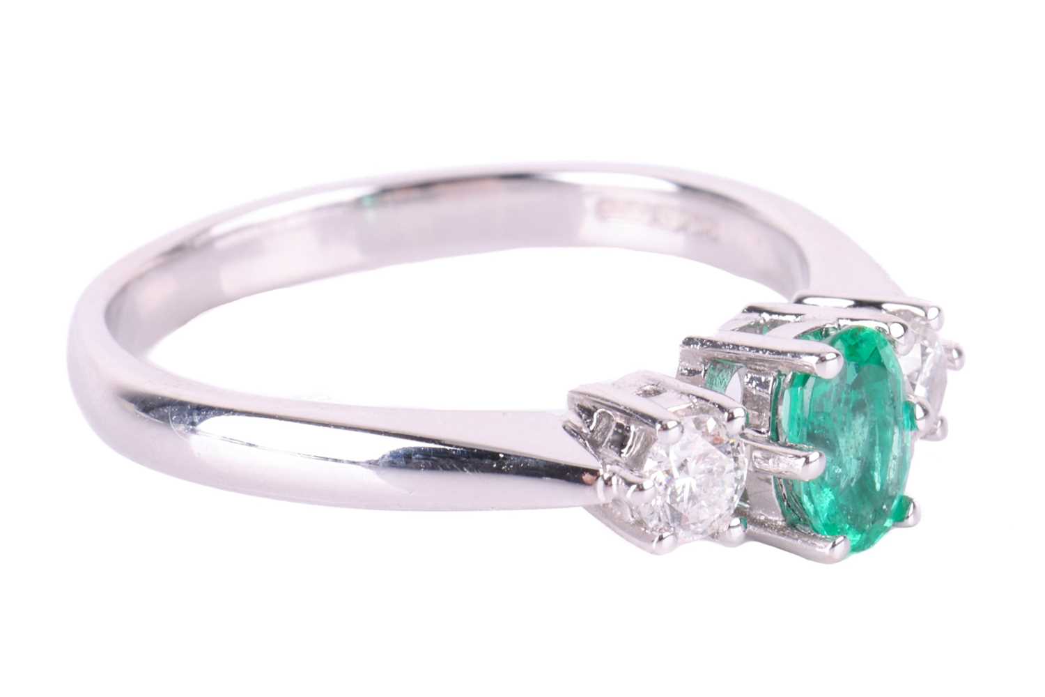 An emerald and diamond trilogy ring in 18ct white gold, centred with an oval-cut emerald of bright g - Image 2 of 4