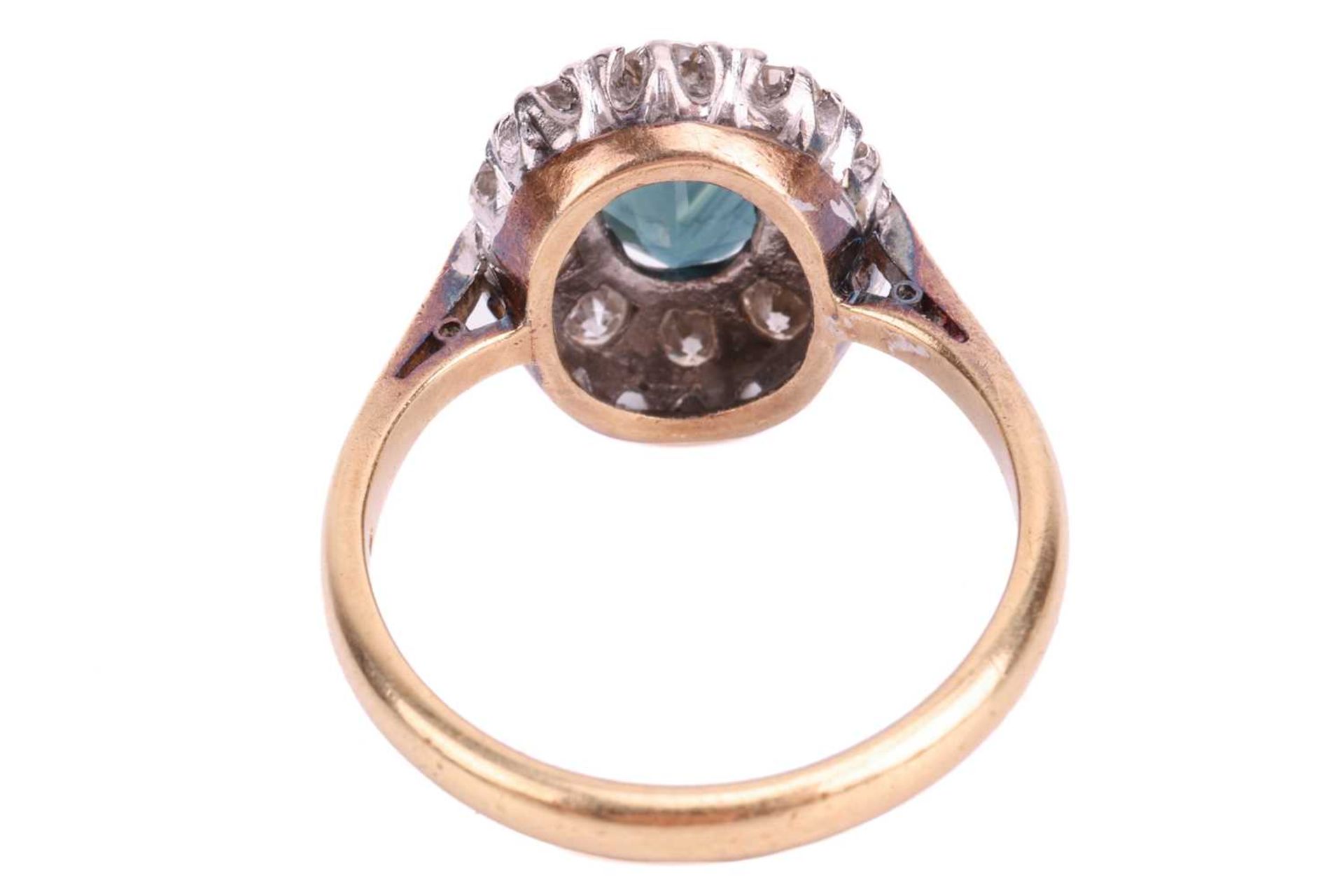 A sapphire and diamond cluster ring, claw-set with an oval-cut sapphire of deep bluish-green colour, - Image 4 of 4