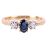 A sapphire and diamond trilogy ring in 18ct gold, centred with an oval-cut sapphire of dark blue col