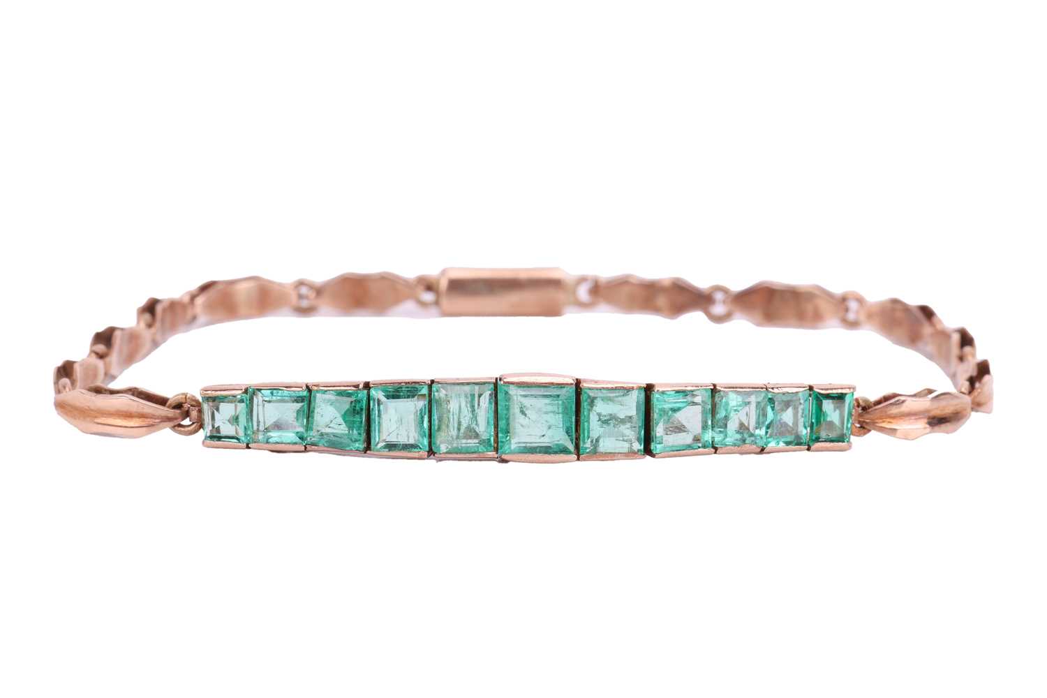 An Art Deco emerald line bracelet, set with a row of eleven graduated calibré cut emeralds, in engra