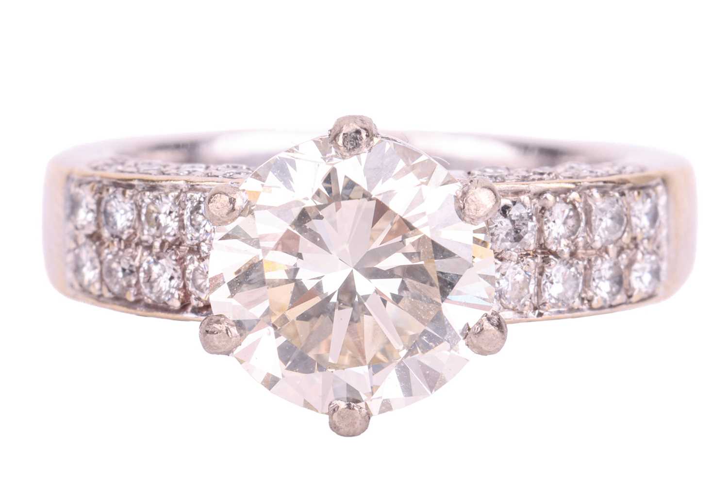 A diamond solitaire ring with diamond set shoulders, featuring a 3.02ct round brilliant cut diamond 