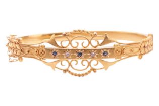 An Edwardian sapphire and diamond hinged bangle, circa 1910, set with a row of sapphires and