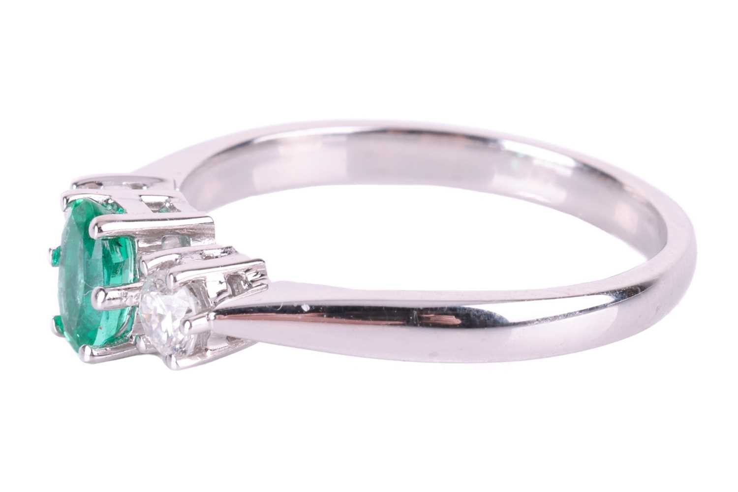 An emerald and diamond trilogy ring in 18ct white gold, centred with an oval-cut emerald of bright g - Image 4 of 4