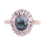 A sapphire and diamond cluster ring, claw-set with an oval-cut sapphire of deep bluish-green colour,