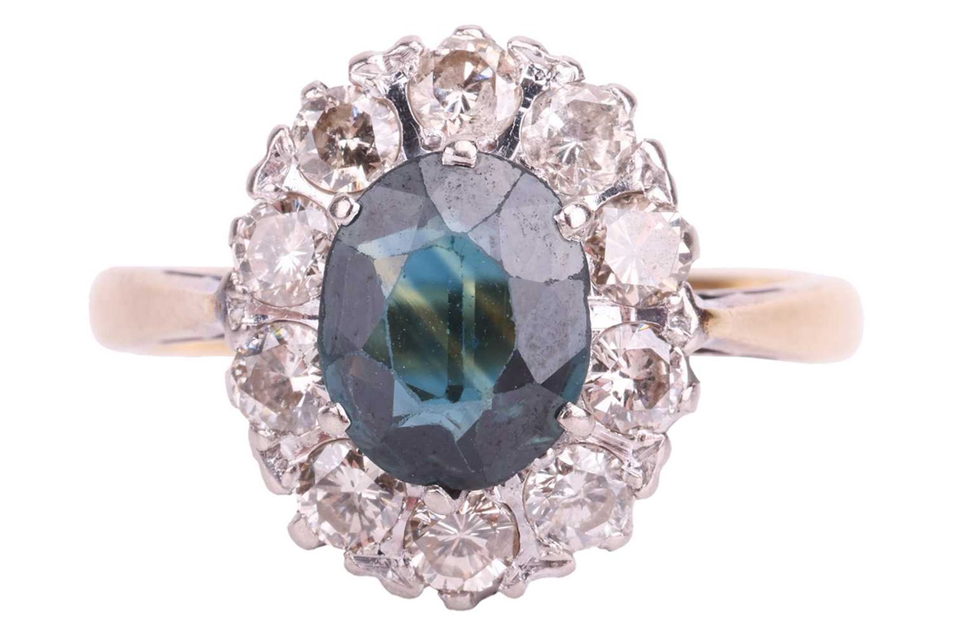 A sapphire and diamond cluster ring, claw-set with an oval-cut sapphire of deep bluish-green colour,