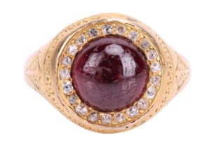 A Victorian garnet and diamond halo ring in 18ct yellow gold, centred with a round garnet cabochon