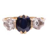 A sapphire and diamond three stone ring, set with a central oval sapphire measuring 7 x 6.2 x 4mm, f