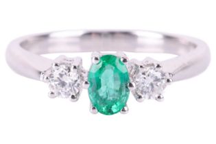 An emerald and diamond trilogy ring in 18ct white gold, centred with an oval-cut emerald of bright