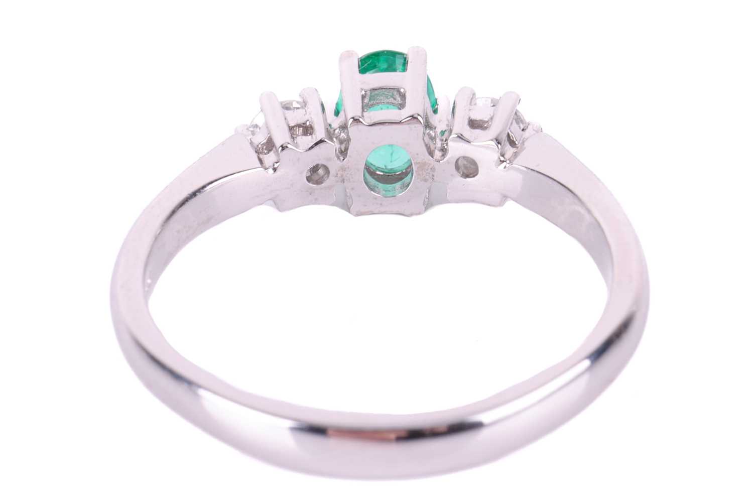 An emerald and diamond trilogy ring in 18ct white gold, centred with an oval-cut emerald of bright g - Image 3 of 4