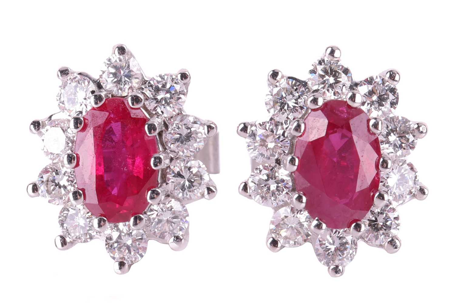 A pair of ruby and diamond cluster earrings, the central oval-cut rubies measuring approximately 6mm