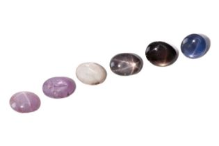 A collection of six loose cabochon sapphires displaying six-ray asterism, including one blue star