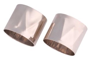 Howard Fenn - a pair of Modernist silver napkin rings with repoussé initials of 'M' and 'W',