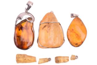 A collection of five amber and copal resin pendants, including a butterscotch amber pendant measurin