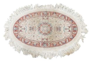 An ivory ground oval Tabriz rug with a central boss with a floral design within a fruiting vine