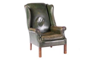 A George III-style wingback fireside chair with close nailed aged bottle green hide stuff over uphol