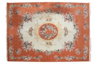 A machine woven ivory ground Tabriz style carpet with circular central boss and a salmon pink border