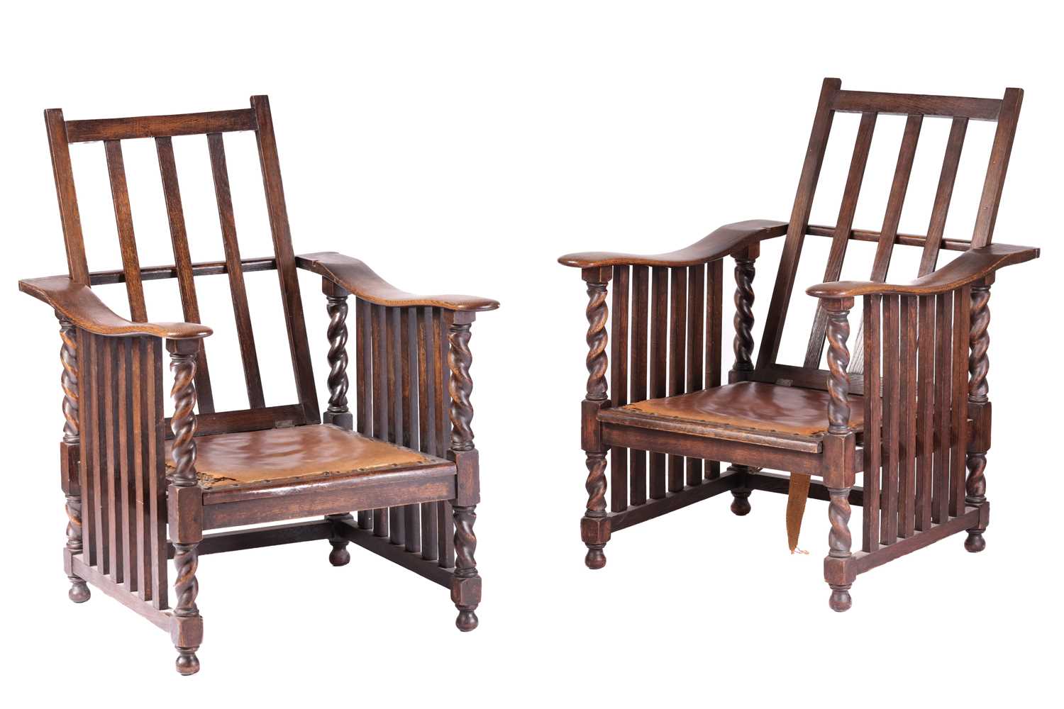 A pair of early twentieth-century reclining oak armchairs in the manner of Jas Shoolbred stood on bu
