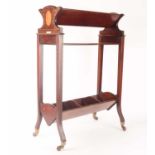 An Edwardian inlaid mahogany three-shelved book trough supported on splayed feet with brass cap cast