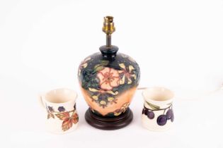 A Moorcroft Oberon patterned lamp base, measuring 28 cm high, alongside two Moorcroft mugs of Plum a