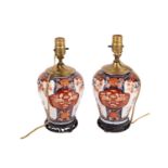 A close pair of Japanese Imari porcelain table lamps, late Meiji period. With carved hardwood stands