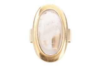 A smoky quartz cabochon dress ring, featuring an elongated oval smokey quartz of 2.3 x 1.1 cm, in a 