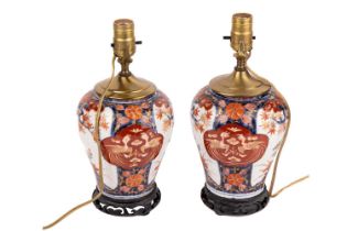 A close pair of Japanese Imari porcelain table lamps, late Meiji period, with carved hardwood