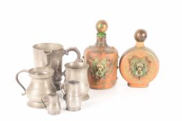 A trio of graduated pewter jugs and two pewter tankards, the largest measures 16 cm tall.