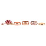 Four wedding rings and two charms; to include an 18ct yellow gold plain wedding band, size M; a simi