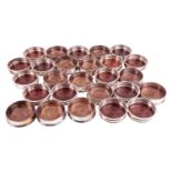 Twenty-six assorted silver-plated wine coasters with turned wooden bases