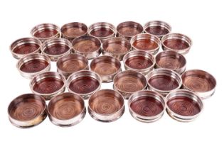 Twenty-six assorted silver-plated wine coasters with turned wooden bases