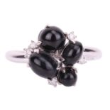 A Whitby jet cabochon cluster ring in 18ct white gold, comprising four oval jet cabochons in various