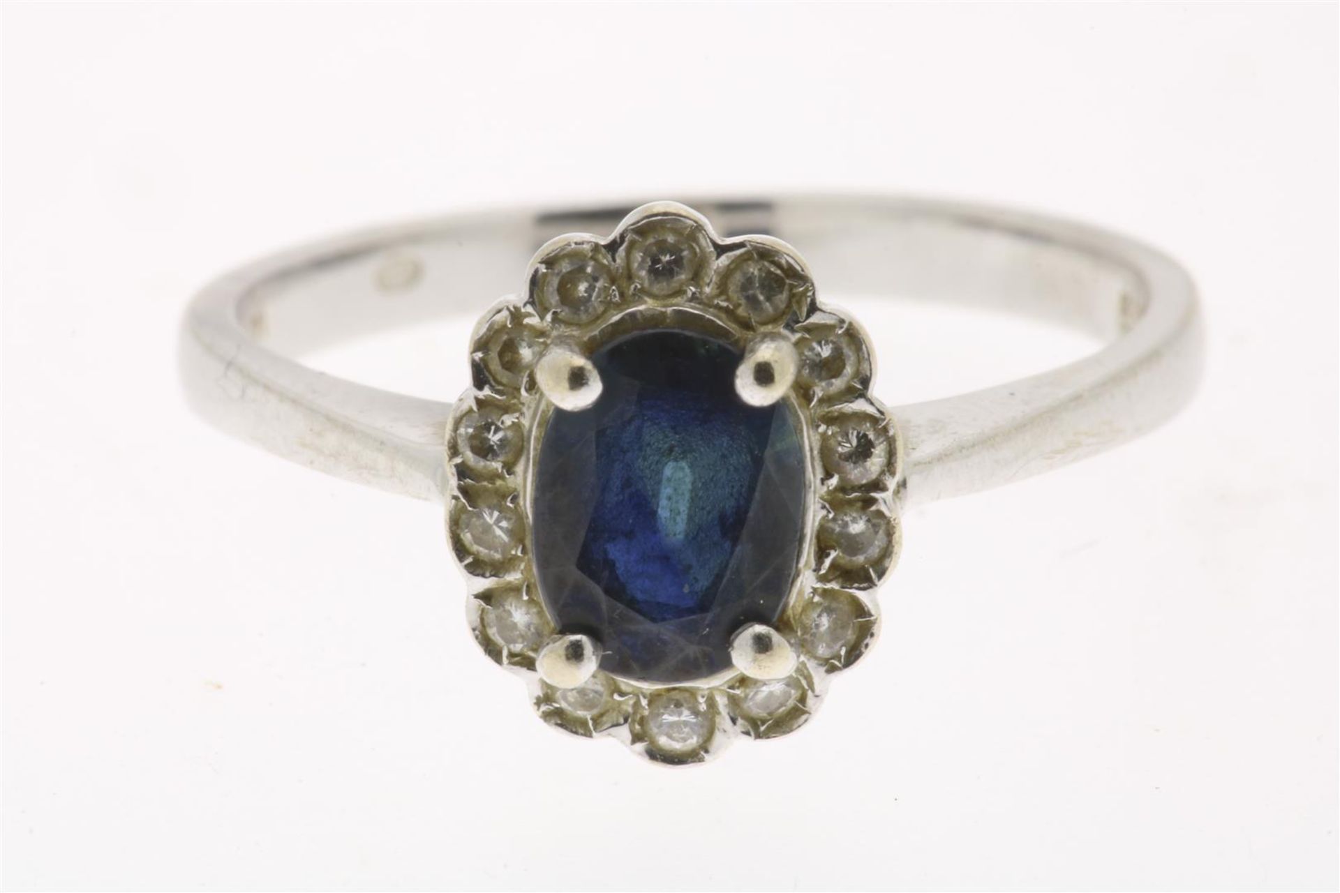 White gold entourage ring, centrally set with a blue colored stone in an entourage of diamonds,