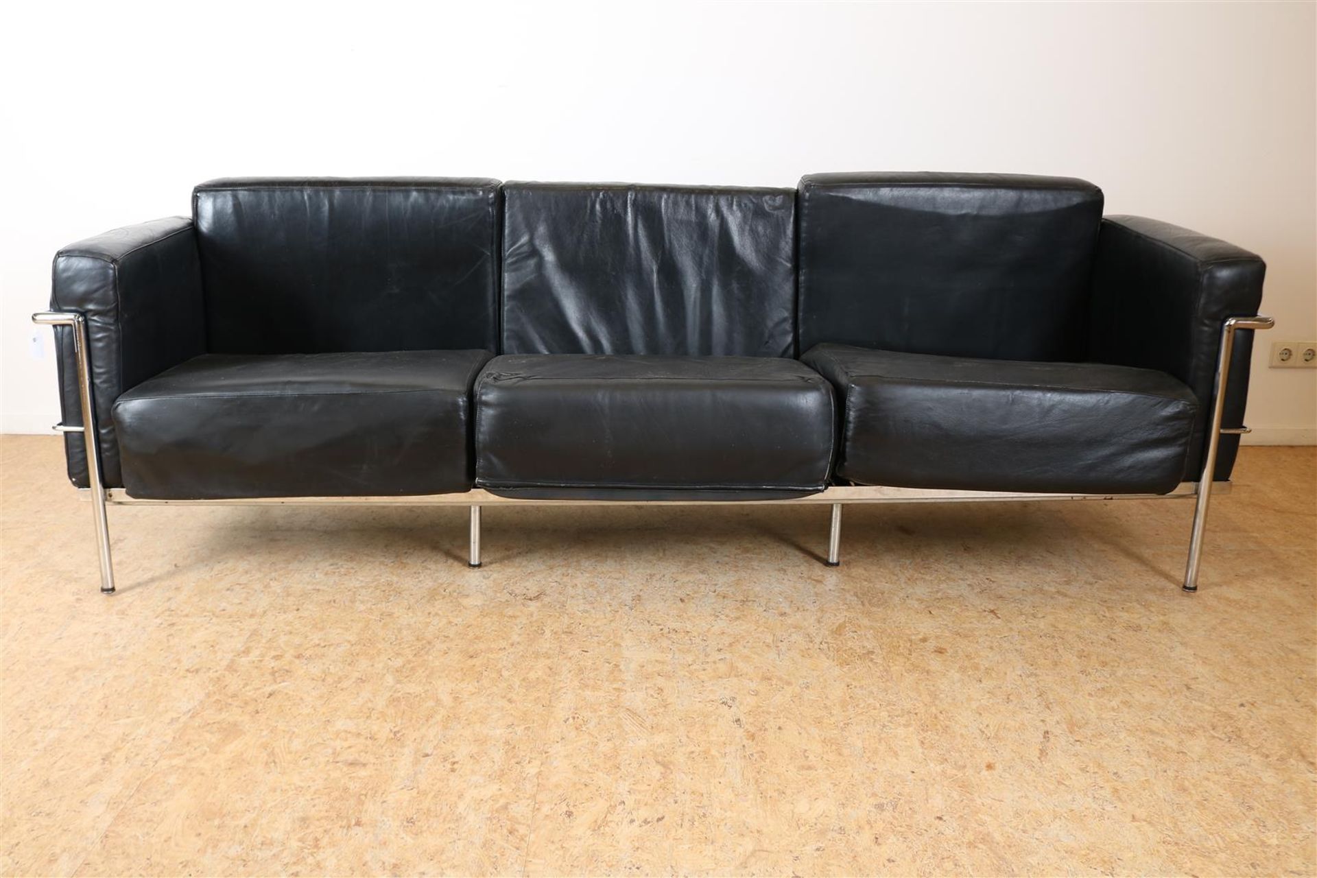 Three-person sofa with black leather cushions on chrome base, modeled after Le Corbusier design,