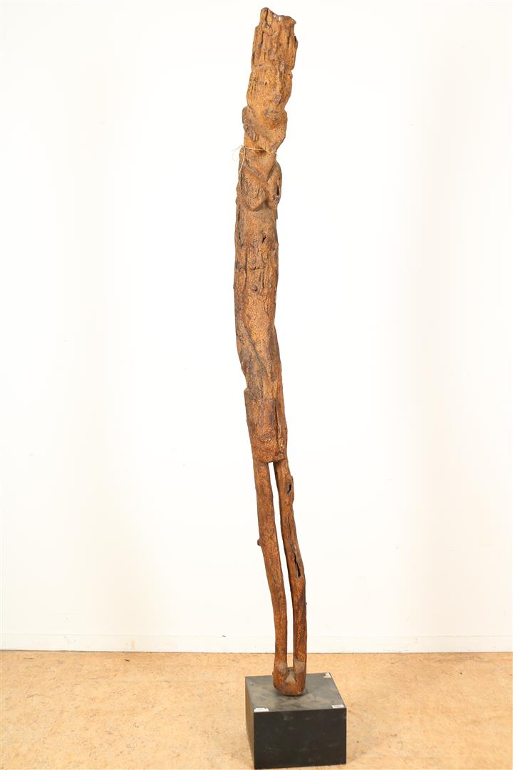 Wooden ancestor statue figure as an elongated male person, probably Dayak Borneo on a pedestal,