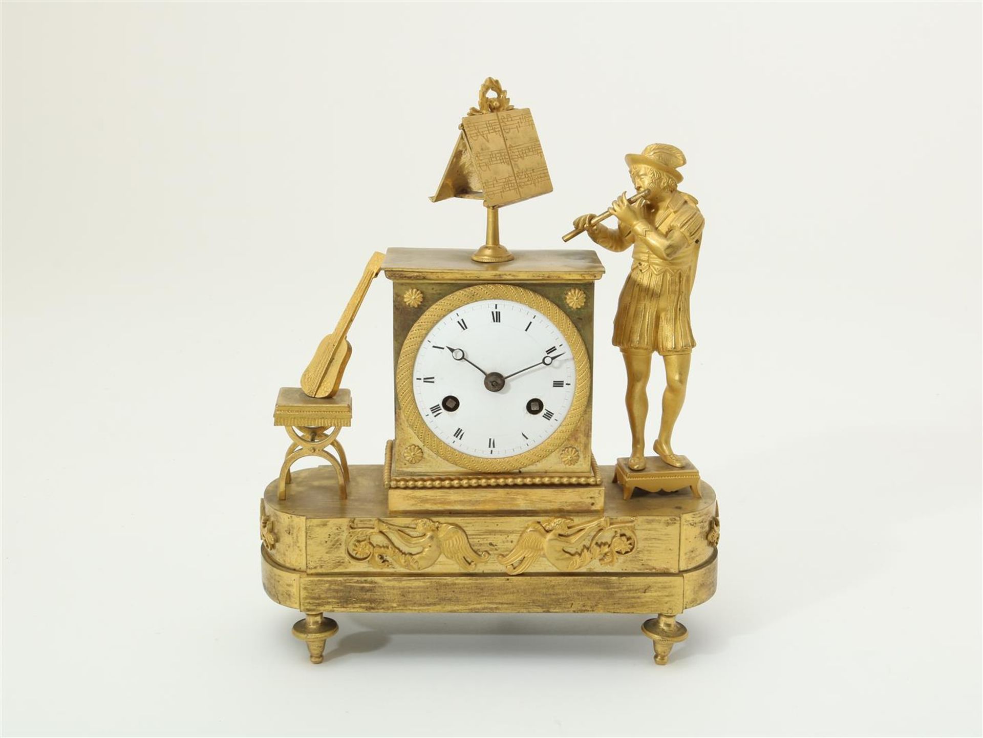 Fire-gilt Empire mantel clock with musician and sheet music, with running and percussion