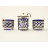 Openwork silver mustard pot with pearl rim and two salt cellars with pearl rim, with blue glass