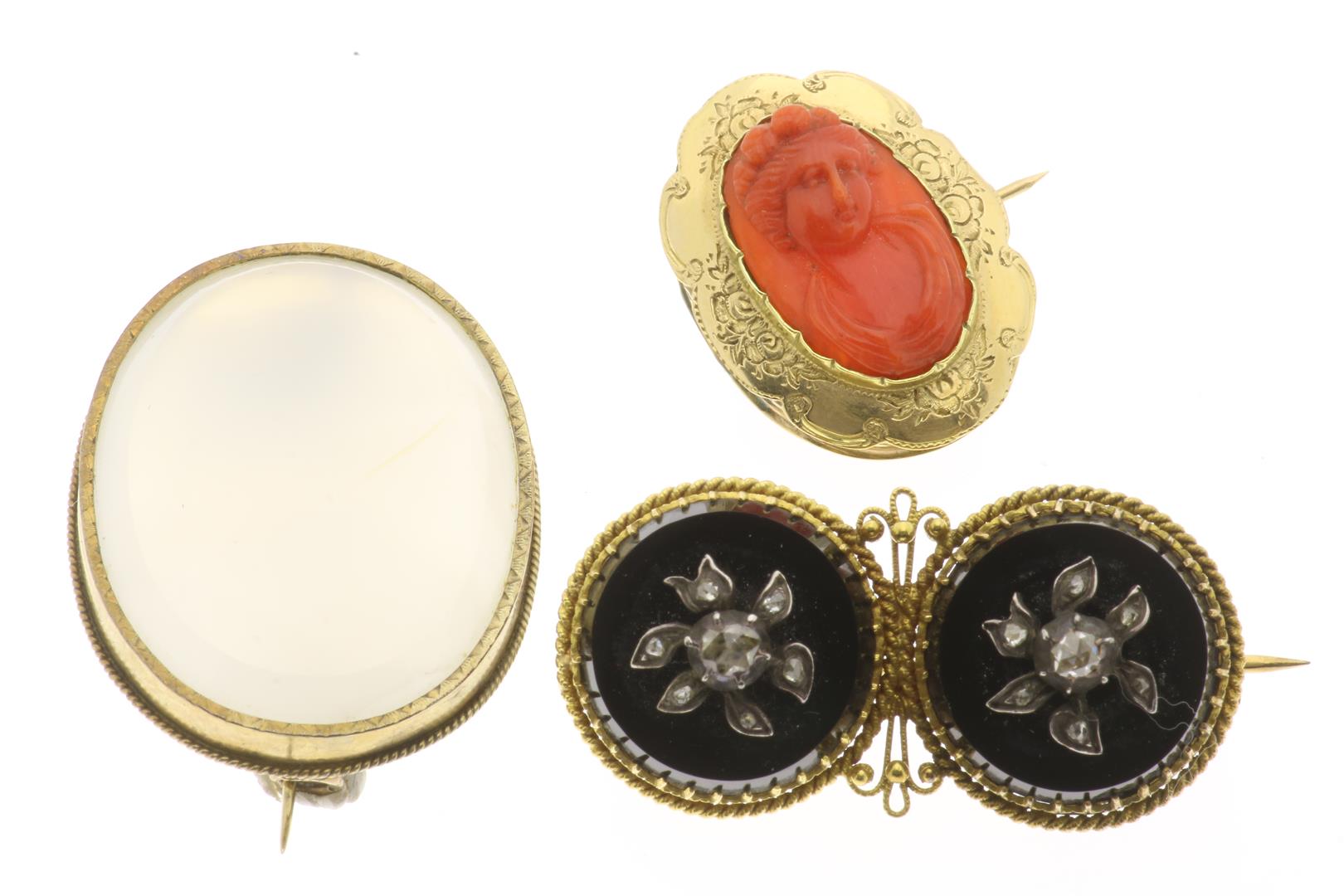 A lot with 3 gold brooches, including one set with carved red coral with a woman in profile; black