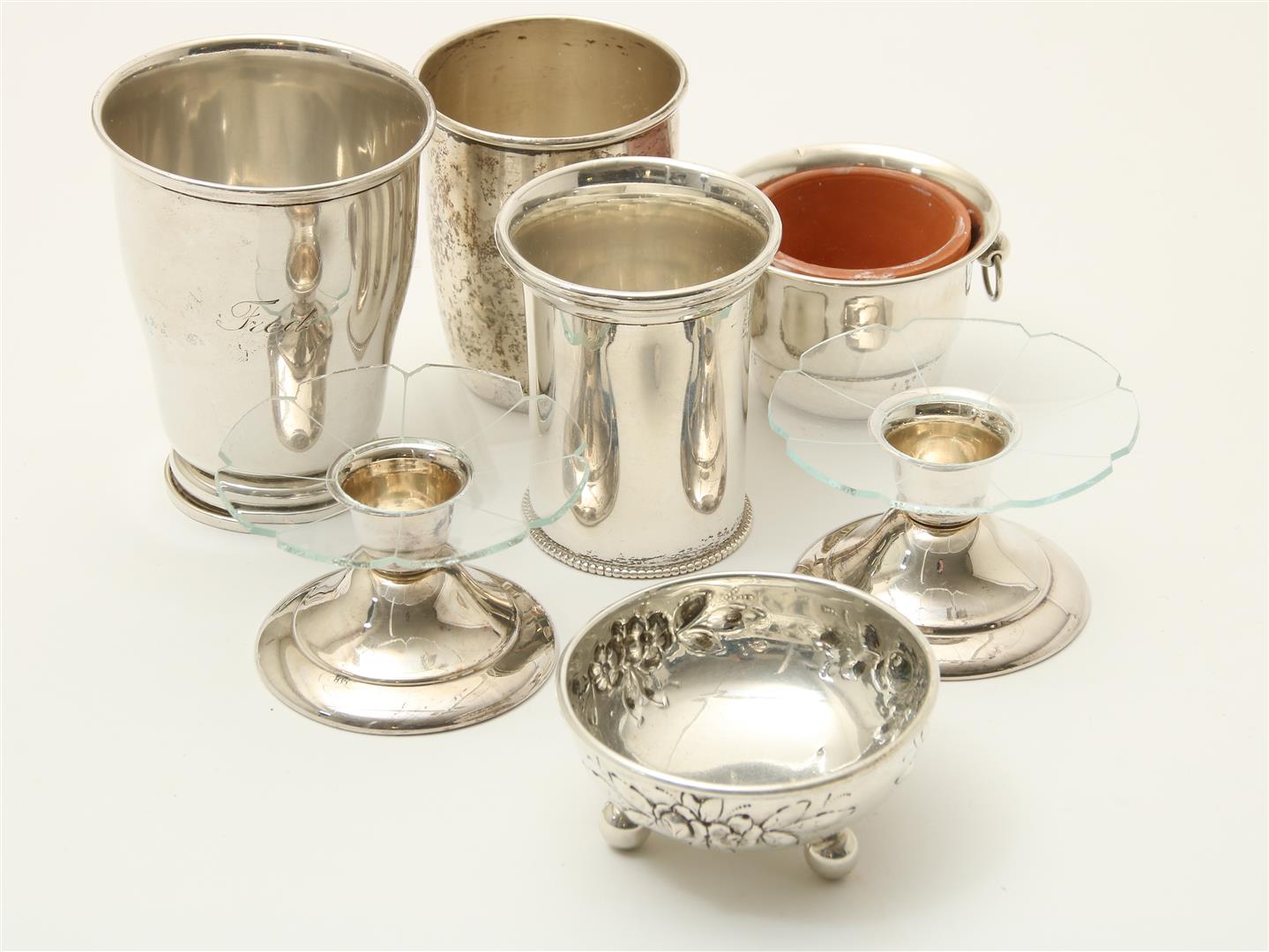 Various silver drinking cups and bowls, including two silver candle holders.