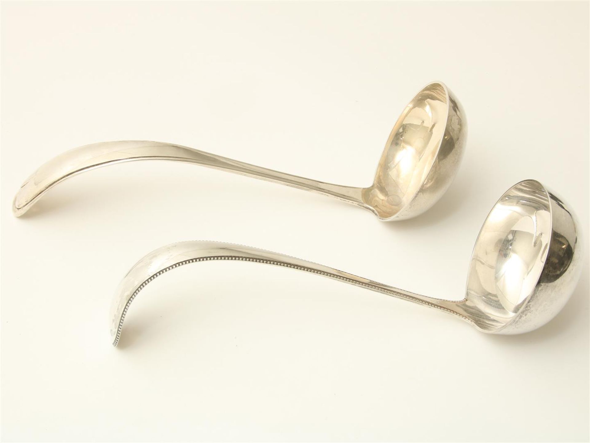 Two silver soup spoons, with pearl rim and heart motif, maker's mark respectively "AK47":