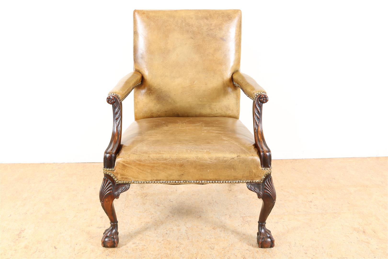 Brown leather armchair on carved legs with fan motifs on ball claw feet.