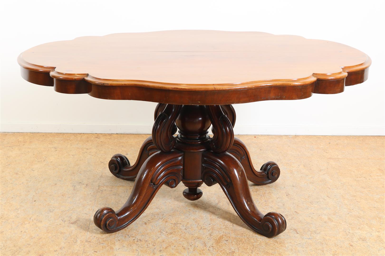 Mahogany Victorian coffee table with contoured top resting on richly carved legs ending in 4-sprant,