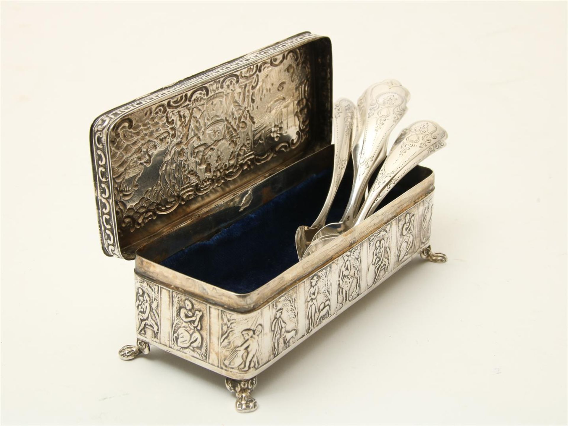 Silver spoon box on claw feet with representations of figures and landscapes, including 7 silver