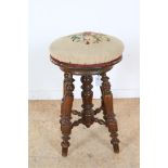 Walnut piano stool with embroidered swivel seat.