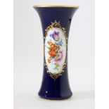 Cylindrical porcelain vase with flower decoration in gold rimmed oval on cobalt blue background,
