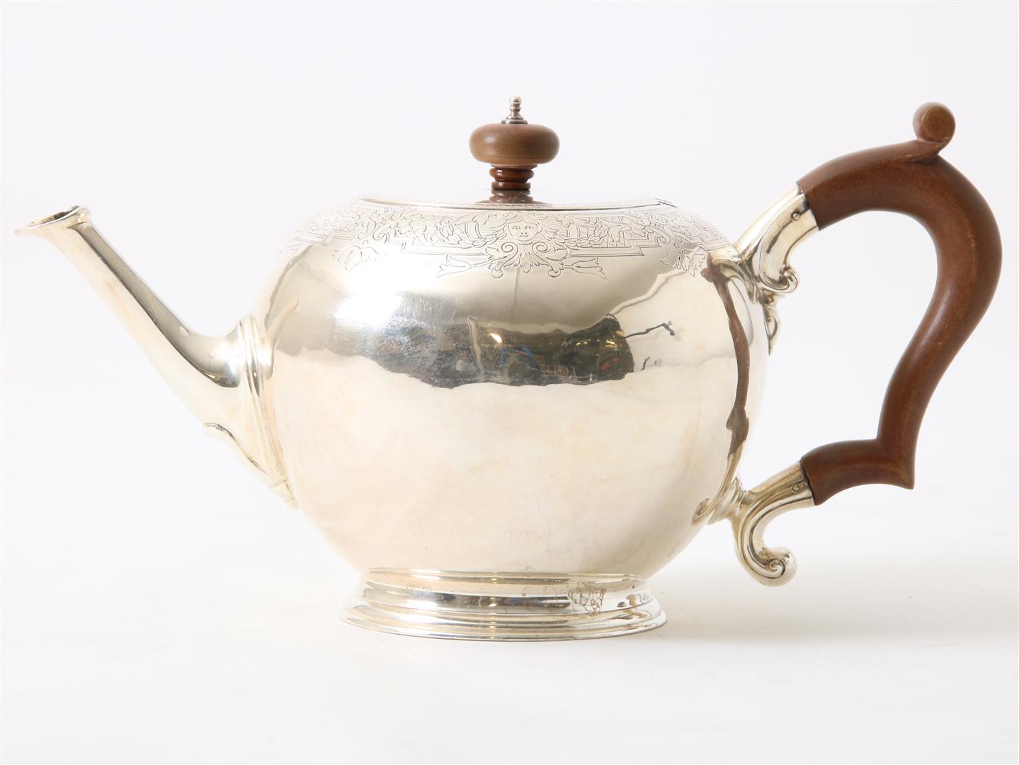 Silver teapot with wooden handle, decorated with floral vines and heads in garlands, England,