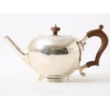 Silver teapot with wooden handle, decorated with floral vines and heads in garlands, England,